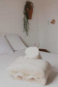uma cama branca com almofadas e uma planta na parede em Casinhas da Serena - Casa concha em Caraíva