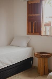 a small bedroom with a bed and a stool at Casinhas da Serena - Casa concha in Caraíva