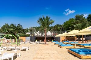 a beach with chairs and umbrellas and a playground at Penzión Aqua Maria in Veľaty