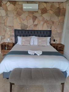 a bedroom with a large bed with a stone wall at Lira Boutique Lodge in Thohoyandou