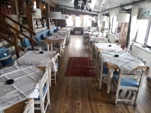 ein Esszimmer mit Tischen und Stühlen und Fenstern in der Unterkunft Sunny Days apartman Kopaonik in Kopaonik