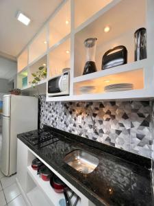 Una cocina con encimera negra y refrigerador. en POUSADA BEIRA MAR, en Fortaleza