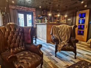 a barber shop with two leather chairs and a chair with a blanket at The Pub - Unique & Authentic Experience - Free Parking!, 5 minutes from Airbus and The Mall Cribbs in Bristol