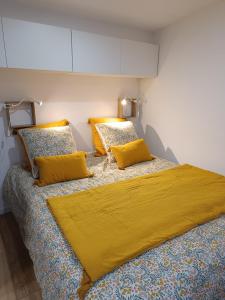 1 Schlafzimmer mit 2 Betten mit gelber Bettwäsche und Kissen in der Unterkunft La pause bretonne in Quéven