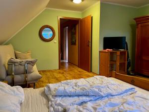 1 dormitorio con 1 cama, TV y silla en Dvoupodlažní zděná chata, en Tábor