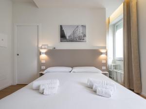 a white bedroom with a large white bed with two pillows at Dome in Cagliari