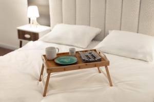 een dienblad met twee kopjes en een bord op een bed bij Blue Harmony Apartment in Floreşti