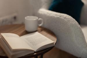 an open book on a table next to a coffee cup at Blue Harmony Apartment in Floreşti