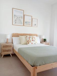 ein Schlafzimmer mit einem Holzbett mit drei Bildern an der Wand in der Unterkunft Ático Ceitil Candor in Rota