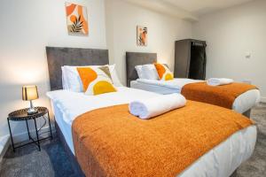 赫爾河畔京士頓的住宿－Luxury City Centre Apartment (Weekly Booking)，一间卧室配有两张带橙色和白色床单的床