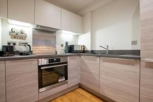 a kitchen with stainless steel appliances and wooden cabinets at Luxury City Centre Apartment (Weekly Booking) in Hull