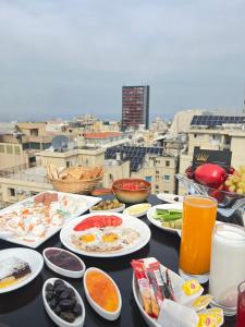 - une table avec des assiettes de nourriture et de boissons au sommet d'une ville dans l'établissement Queens Suite Hotel, à Beyrouth
