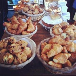 a table topped with bowls of pastries and croissants at Anita's Bed & Breakfast - Bedroom On Ground Floor With Backyard in Abbotsford