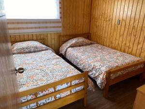 two beds in a room with wooden walls at Cabaña con vista al mar Dalcahue 6 personas in San Javier
