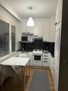 a kitchen with white appliances and a table and chairs at Tilava yksiö Niinivaaralla in Joensuu