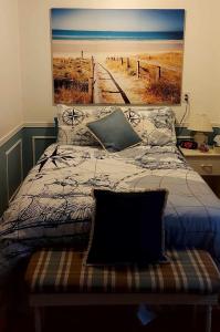 1 dormitorio con 1 cama con una pintura en la pared en Gîte Au p'tit bonheur B&B, en Coaticook