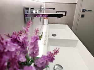 baño con lavabo con flores púrpuras en Il Sogno di Giò en Alghero