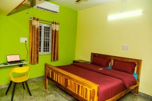 Un dormitorio con una cama con paredes verdes y un escritorio. en Sri Sakthi Residence en Tiruvannāmalai