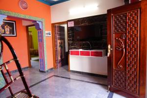 Habitación con paredes de color naranja y cocina con TV. en Sri Sakthi Residence en Tiruvannāmalai