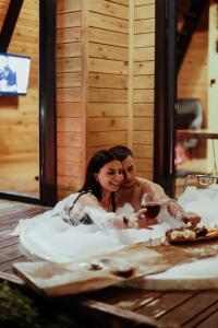a man and woman sitting in a bath tub with a glass of wine at Doğa Bungalow Sapanca in Sakarya