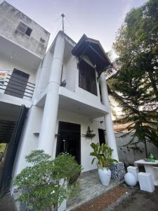una casa blanca con columnas y plantas en Black Bird Villa, en Uragasmanhandiya