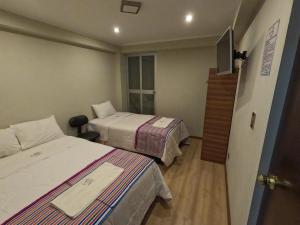 Cette chambre comprend deux lits et une télévision. dans l'établissement Millpu Hostal, à Ayacucho