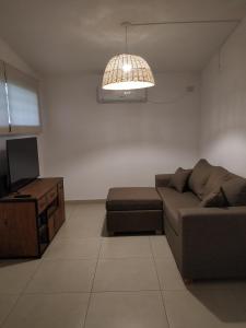 a living room with a couch and a television at Casa 4 amb y cochera Don Bosco in Córdoba