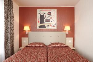 a bedroom with a bed with red walls and two lamps at Hotel Miramar in Paris