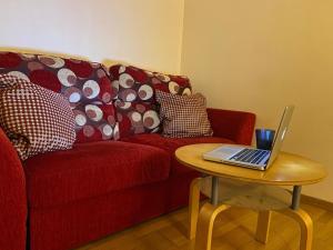 a red couch with a table with a laptop on it at Casina di ZiaMar in Rome