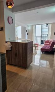 a living room with a cabinet and a pink chair at Apartamento encanto urbano. in Barranquilla