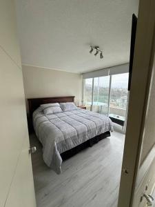 a bedroom with a bed and a large window at Departamento full equipado in Viña del Mar