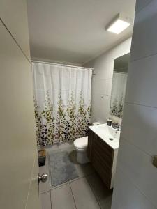 a bathroom with a toilet and a shower curtain at Departamento full equipado in Viña del Mar