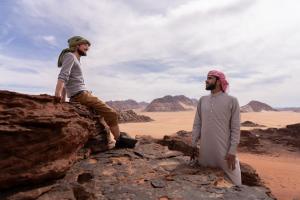 two men standing on a rock in the desert at desert colored camp in Wadi Rum