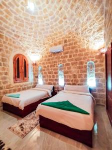 2 camas en una habitación con una pared de piedra en كمبوند قرية تونس en Tunis