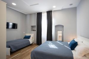 sypialnia z dwoma łóżkami i telewizorem na ścianie w obiekcie Tredidenari B&B w mieście Salerno