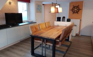 a kitchen with a wooden table with chairs and a tv at Vakantiehuis Ruby in Bruinisse