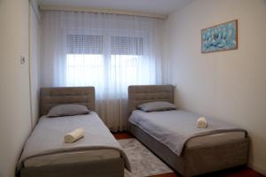 two twin beds in a room with a window at Triple A Apartments in Sarajevo
