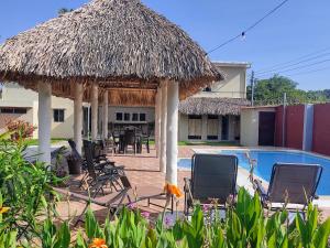 un complejo con piscina, sillas y una cabaña de paja en Rancho Del Oso Tuerto en Marcelino