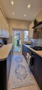 una cucina con armadi blu e un tappeto sul pavimento di Stunning 3 bedroom semi detached house! a Goodmayes