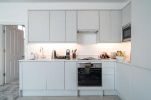 a white kitchen with white cabinets and a dishwasher at Niru Experience Royal Deluxe 4BD 2BA Apt in London