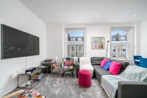 een woonkamer met een bank en een flatscreen-tv bij Niru Experience Royal Deluxe 4BD 2BA Apt in Londen