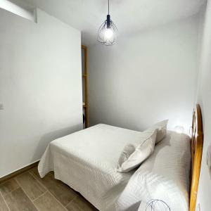 a bedroom with a white bed and a lamp at Bajo Derecha el Wiro in Puerto