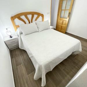 een slaapkamer met een wit bed en een houten hoofdeinde bij Bajo Derecha el Wiro in Puerto