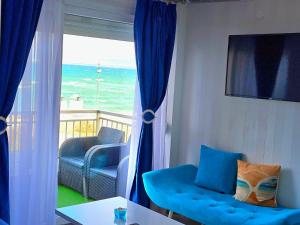 a living room with a blue couch and a balcony with the ocean at SUN SEA No 3 in Perea