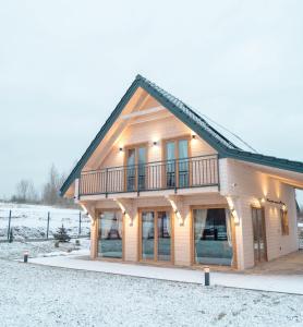 uma casa de madeira com um telhado de gambrel na neve em Gwiazda Północy Gołdap Dom VIP na Wynajem em Gołdap