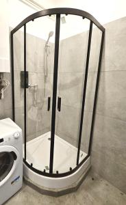 prysznic ze szklanymi drzwiami obok pralki w obiekcie Pomorska86 Aparts - Łódź Centrum w Łodzi