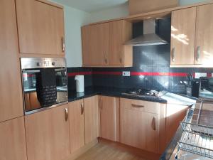 a kitchen with wooden cabinets and a stove top oven at Perfect Stay Manchester in Wythenshawe