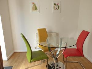 a glass table with four green chairs in a room at Perfect Stay Manchester in Wythenshawe