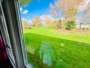 a window with a view of a green yard at 40A Oak Village- 2 Bedroom Lodge on Grange Leisure Park in Mablethorpe