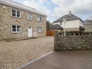 uma casa de tijolos com uma cerca de pedra em frente em About Time Cottage em Lydney